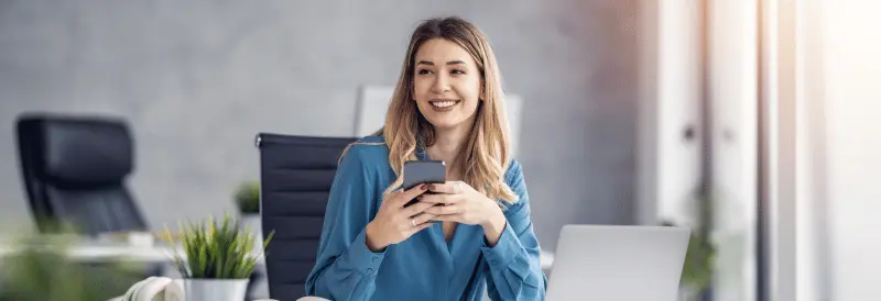 Kobieta trzymająca telefon siedząca przy biurku